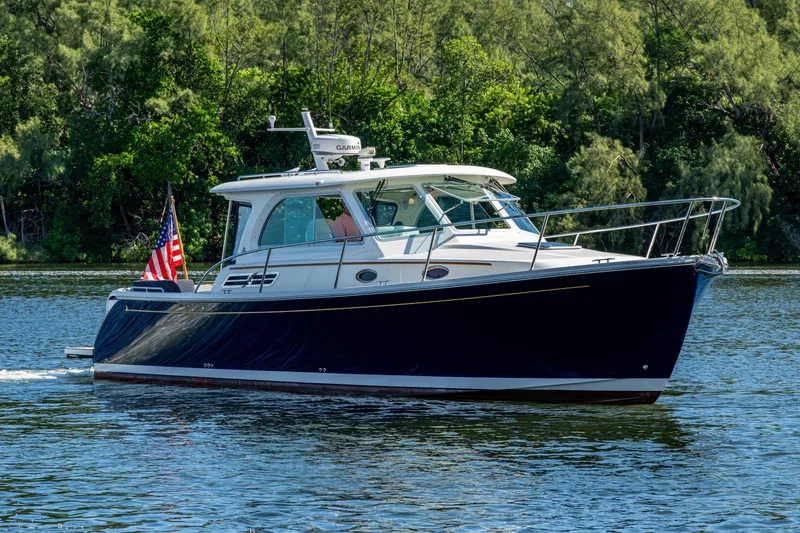 Slide: The Image of 2020 Back Cove 340 boat cruising on a serene lake with lush greenery. - 52