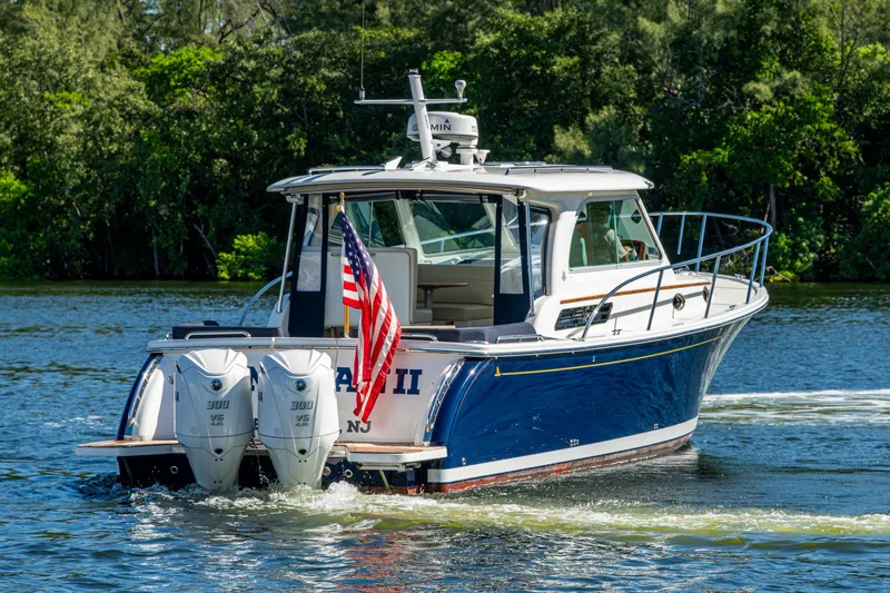 Slide: The Image of 2020 Back Cove 340 boat cruising on a scenic waterway with American flag. - 54