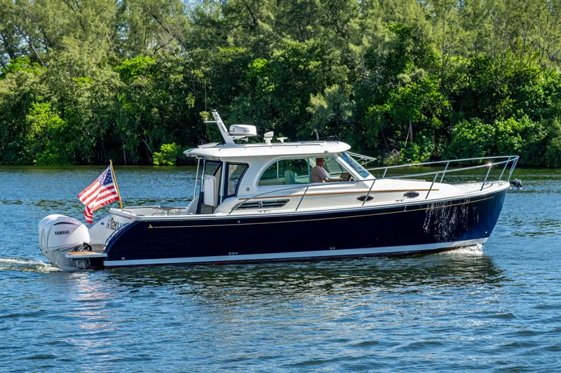 Slide: The Image of 2020 Back Cove 340 boat cruising on a scenic waterway with lush greenery. - 56