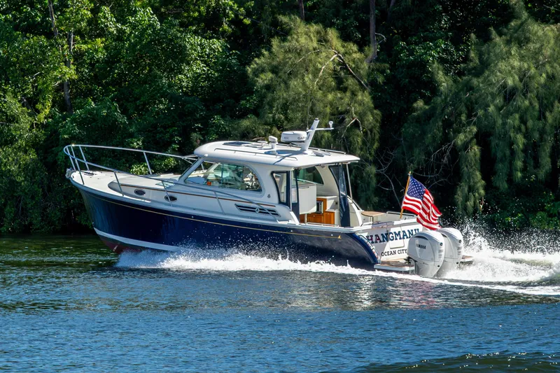 Slide: The Image of 2020 Back Cove 340 boat cruising on a river with lush greenery background. - 60