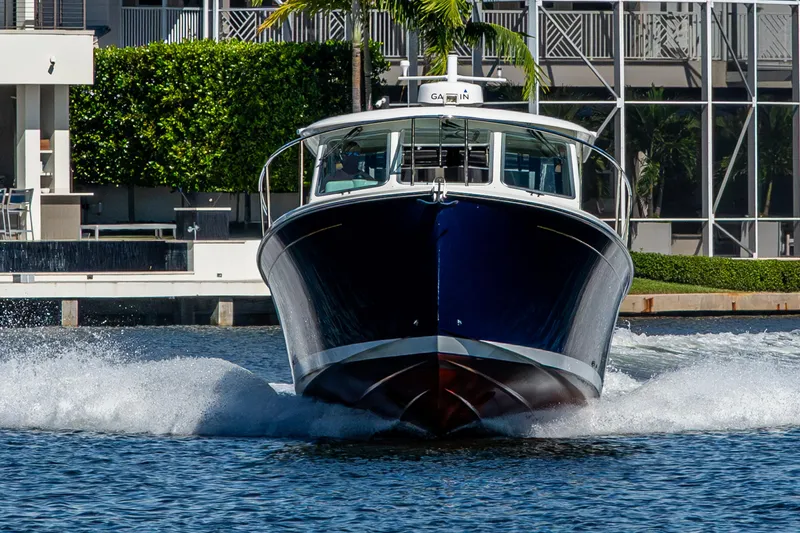Slide: The Image of 2020 Back Cove 340 boat cruising on water near modern waterfront property. - 63