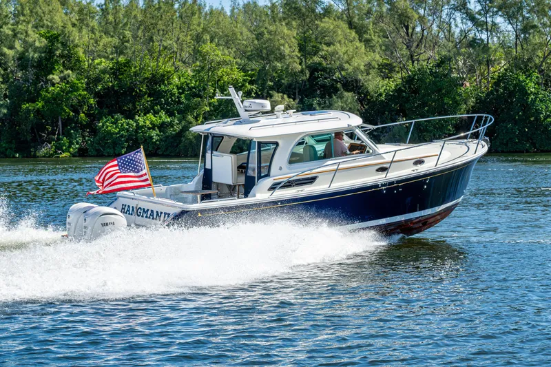 Slide: The Image of 2020 Back Cove 340 boat cruising on a scenic waterway with American flag. - 68
