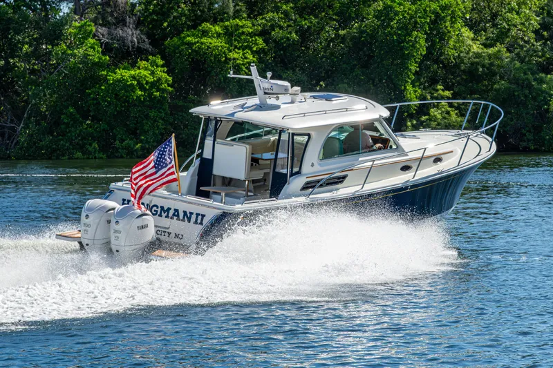 Slide: The Image of 2020 Back Cove 340 boat cruising on a sunny day, displaying an American flag. - 69