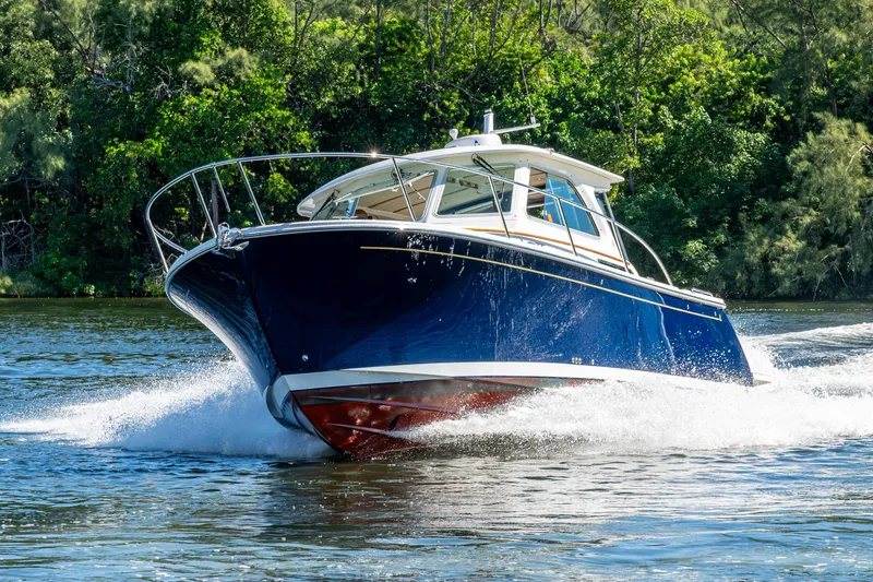 Slide: The Image of 2020 Back Cove 340 boat cruising on a scenic waterway with lush greenery. - 72