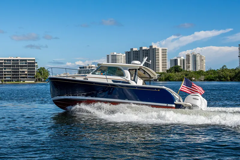 Slide: The Image of 2020 Back Cove 340 boat cruising on water with city skyline backdrop. - 74