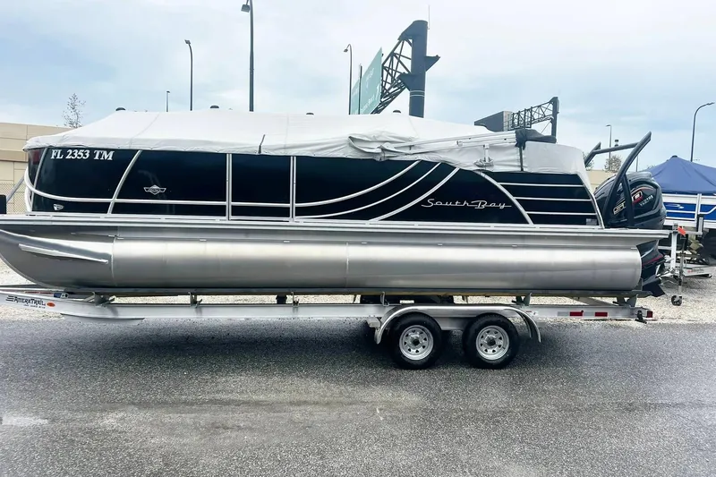 The Image of 2023 South Bay 523 R pontoon boat on trailer, covered and parked outdoors. - 1