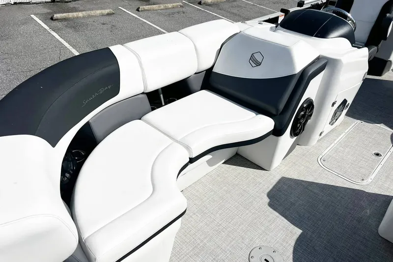 Slide: The Image of 2023 South Bay 523 R boat interior with white and black seating in a parking lot. - 7