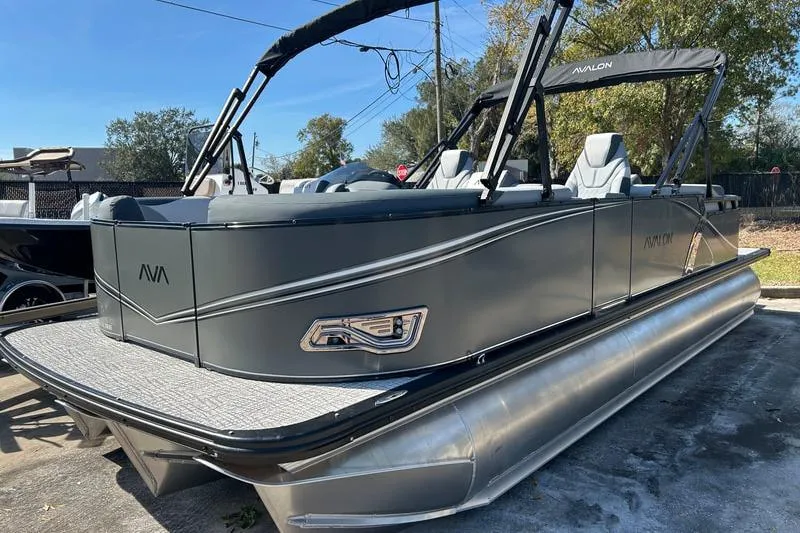 The Image of 2025 Avalon LSZ Quad Lounger pontoon boat in a parking lot, showcasing sleek design. - 0