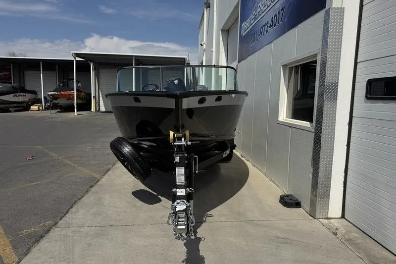 Slide: The Image of 2025 Alumacraft Competitor 185X Sport boat parked outside a building. - 1