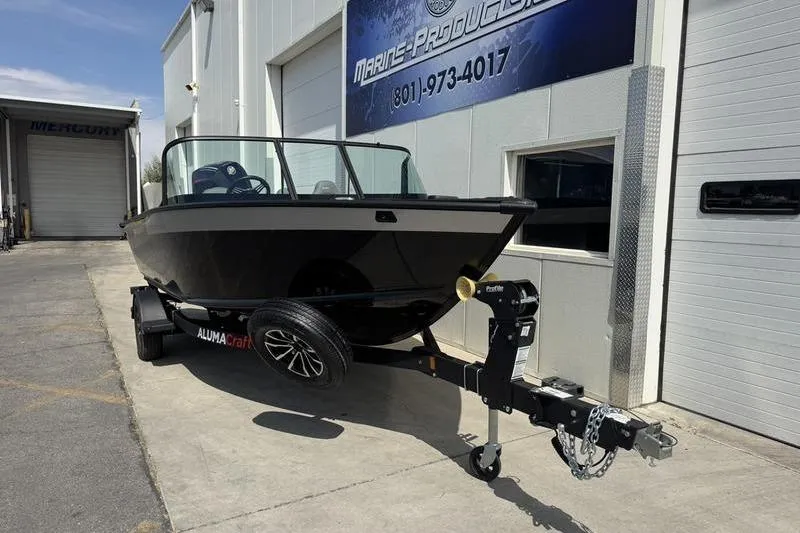 Slide: The Image of 2025 Alumacraft Competitor 185X Sport boat on trailer outside marine dealership. - 2