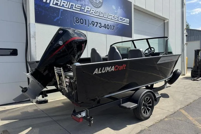 Slide: The Image of 2025 Alumacraft Competitor 185X Sport boat with outboard motor, parked outside a marine shop. - 3