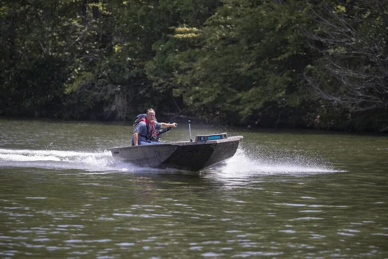 Slide: The Image of 2026 Xpress X18DB boat speeding on a lake with lush green trees in the background. - 5