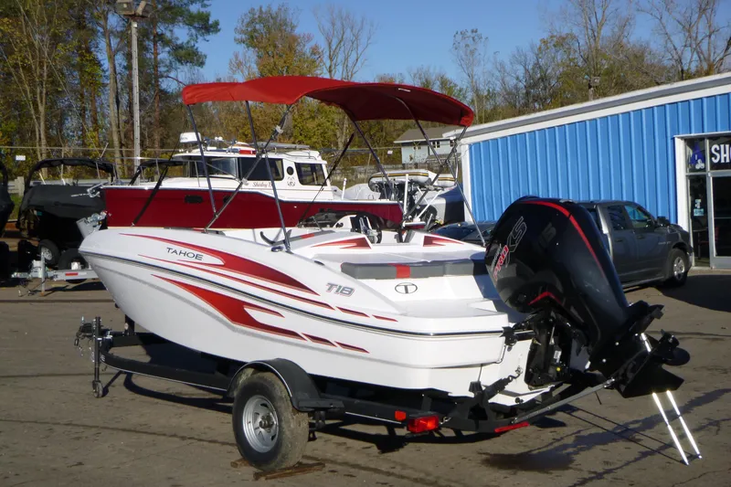 Slide: The Image of 2024 Tahoe T18 boat with red canopy and trailer, parked outdoors. - 4