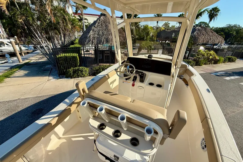 Slide: The Image of 2025 Scout 215 XSF boat interior with helm, seating, and cup holders in a sunny marina. - 12