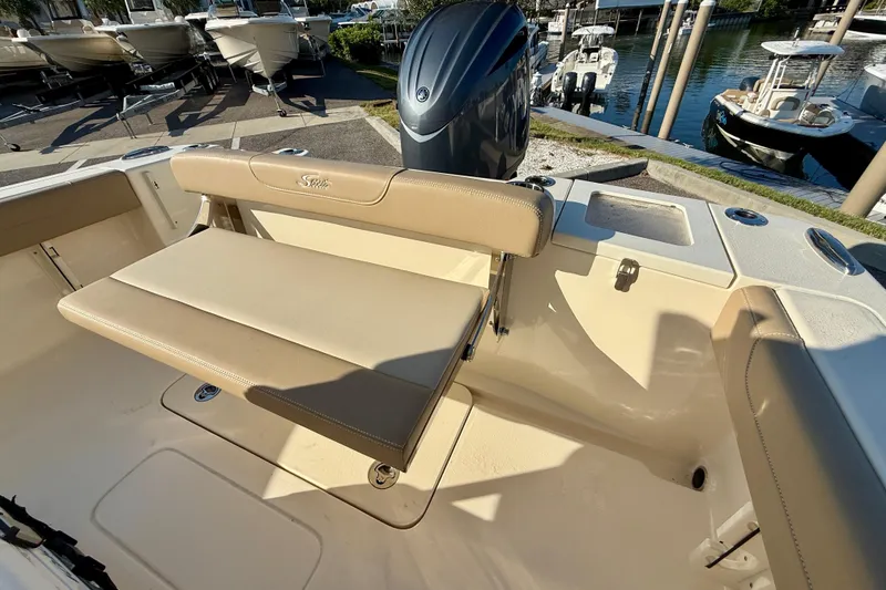 Slide: The Image of 2025 Scout 215 XSF boat interior with beige seating and motor, docked at marina. - 7