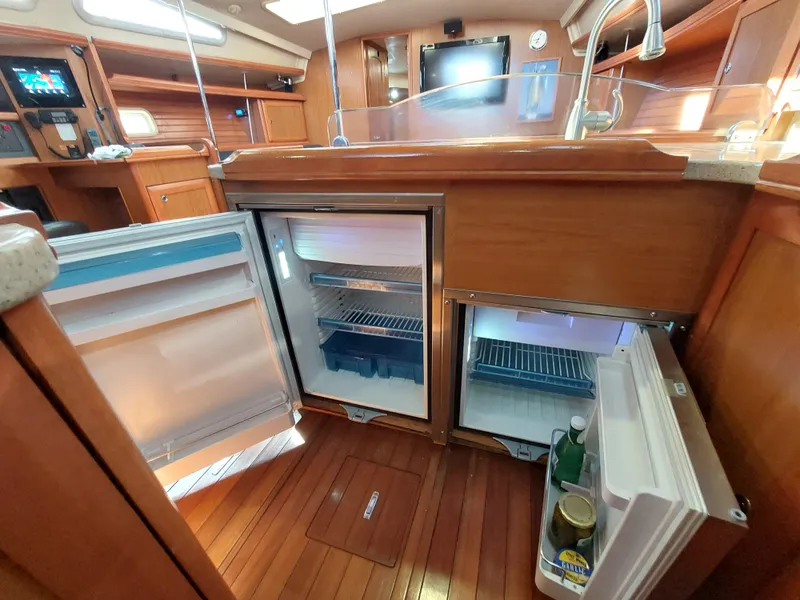 Slide: The Image of 2009 Hunter 49 yacht interior with open fridge, wooden flooring, and modern kitchen amenities. - 23
