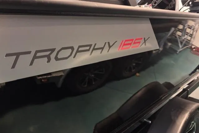 Slide: The Image of 2025 Alumacraft Trophy 185X Sport boat, side view with model name visible. - 3