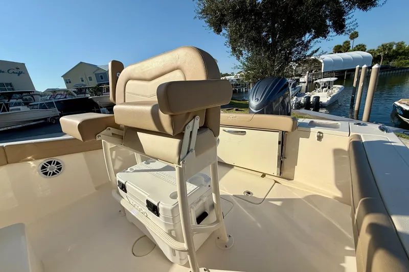 Slide: The Image of 2025 Scout 215 XSF boat interior with seating and storage, docked near other boats. - 9