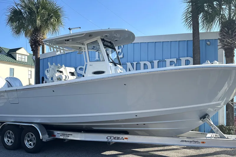 The Image of 2026 Cobia 285 Open Center Console boat on trailer, displayed outdoors. - 1