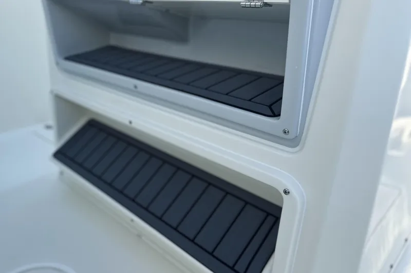 Slide: The Image of 2026 Cobia 285 Open Center Console storage compartments with black non-slip surfaces. - 29