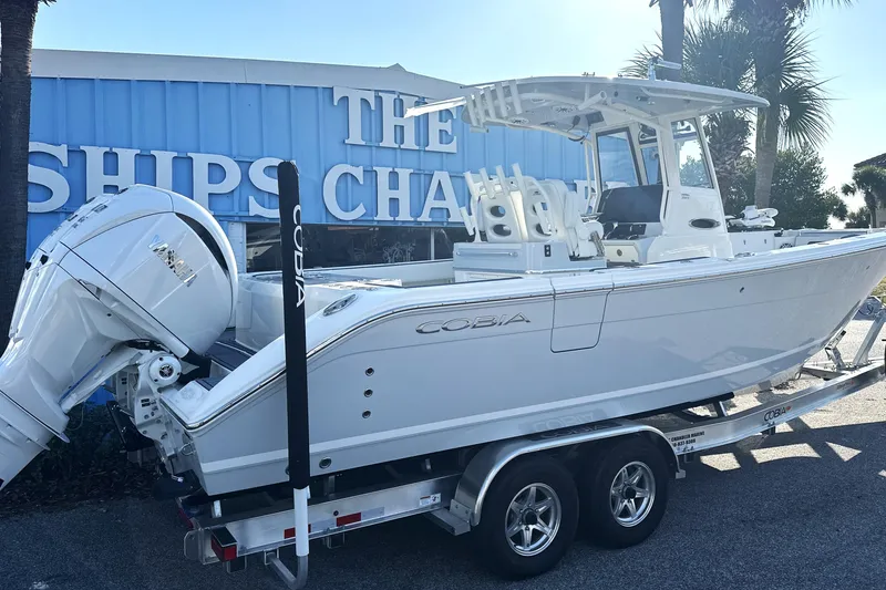 Slide: The Image of 2026 Cobia 285 Open Center Console boat on trailer outside dealership. - 3