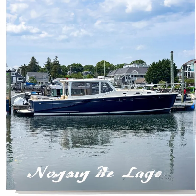 The Image of 2017 MJM 40z Downeast boat docked in a marina, surrounded by coastal homes. - 0