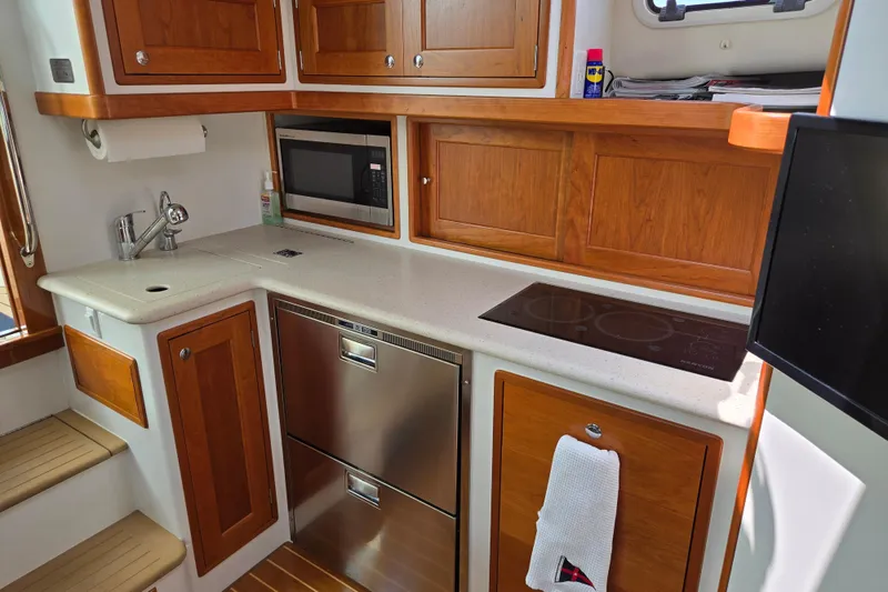 Slide: The Image of 2017 MJM 40z Downeast yacht kitchen with wood cabinets, sink, microwave, and stovetop. - 30