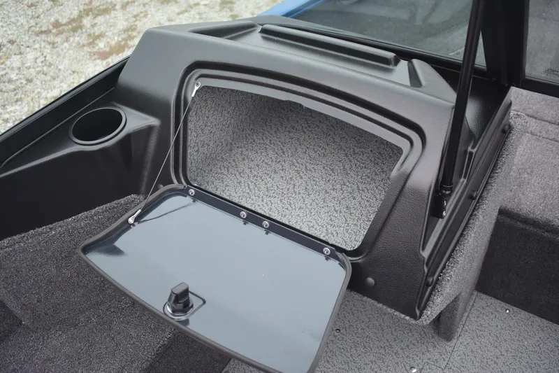 Slide: The Image of 2026 Lund 1650 Rebel XL Sport boat storage compartment with open hatch and cup holder. - 12