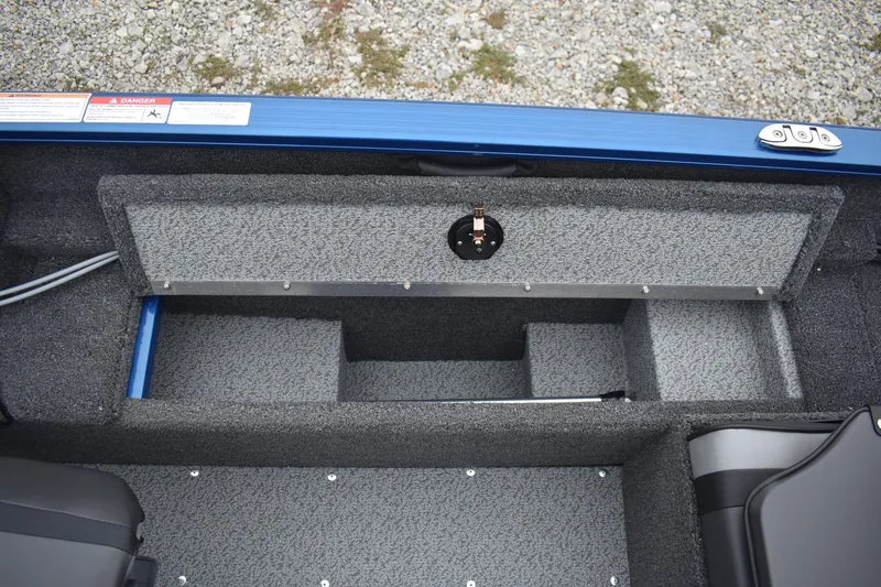 Slide: The Image of 2026 Lund 1650 Rebel XL Sport boat interior storage compartment, gray carpeted finish. - 13