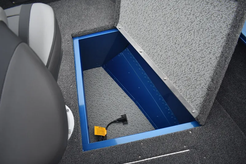 Slide: The Image of 2026 Lund 1650 Rebel XL Sport boat storage compartment with blue interior and gray carpet. - 20