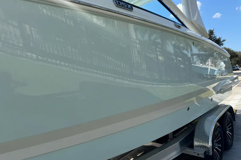 Slide: The Image of 2024 Chaparral 280 OSX boat side view on trailer, reflecting surroundings. - 21