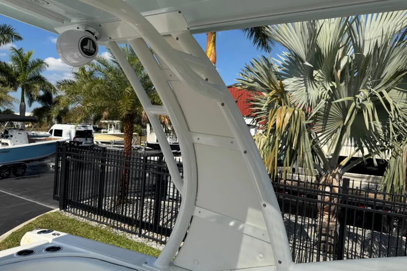 Slide: The Image of 2024 Chaparral 280 OSX boat detail with speaker, palm trees, and parked boats in background. - 38