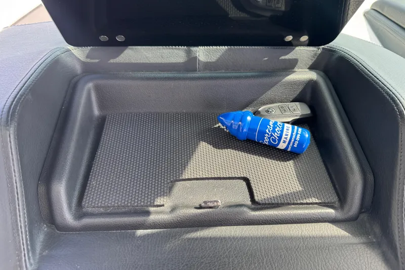 Slide: The Image of 2024 Chaparral 280 OSX storage compartment with key fob and marine cleaner bottle. - 73
