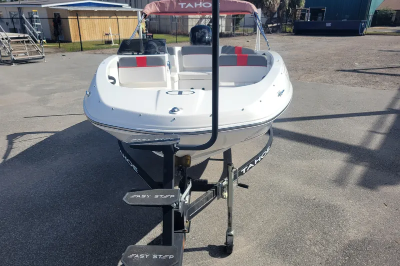 Slide: The Image of 2022 Tahoe T16 boat on trailer, parked outdoors, featuring white hull and red accents. - 2