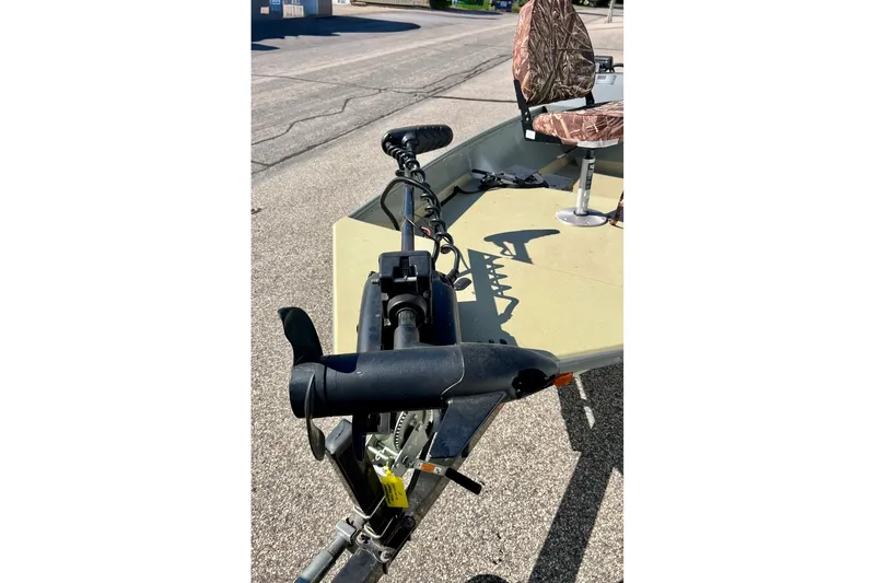 Slide: The Image of 2004 MirroCraft 1876 Outfitter boat with trolling motor and camo seat on pavement. - 24