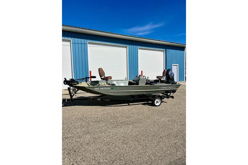 Slide: The Image of 2004 MirroCraft 1876 Outfitter boat parked outside blue building. - 27