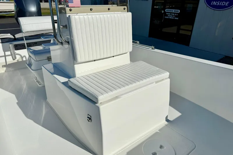 Slide: The Image of 2024 Lookout Bay 19 boat interior with white cushioned seating and storage. - 16