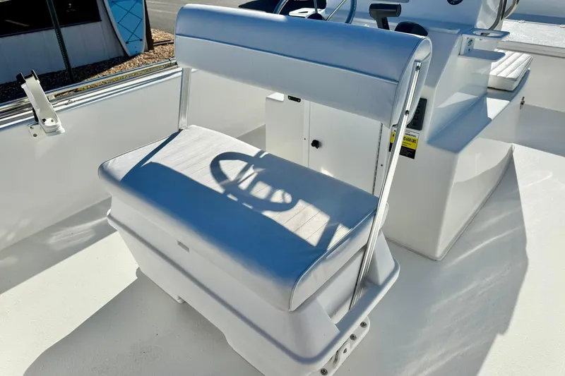 Slide: The Image of 2024 Lookout Bay 19 boat seat with white upholstery and steering console. - 19