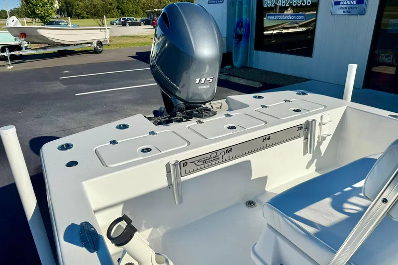 Slide: The Image of 2024 Lookout Bay 19 boat with Yamaha 115 engine, parked outside a marine service shop. - 26