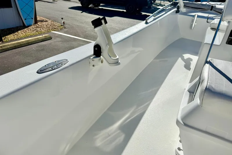 Slide: The Image of 2024 Lookout Bay 19 boat interior with rod holder and seating, parked outdoors. - 28