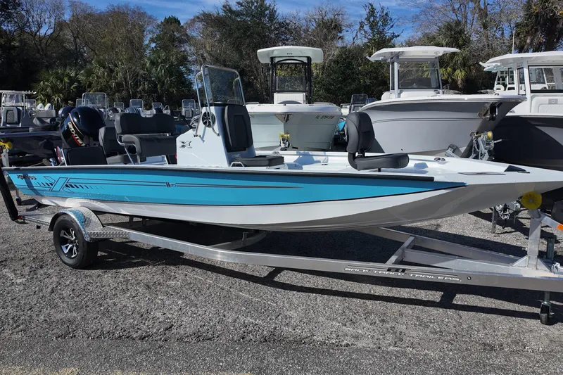 The Image of 2026 Xpress H20B Bay boat on trailer, blue and white design, parked outdoors. - 0