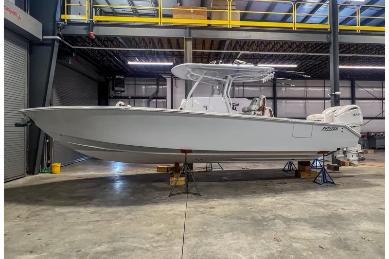The Image of 2026 Jupiter 32 boat in a warehouse, elevated on stands, showcasing sleek design. - 0