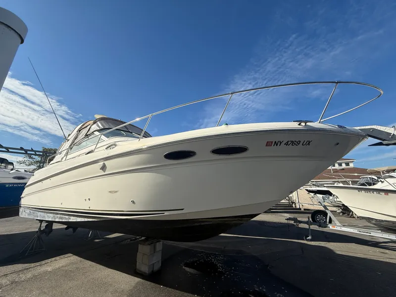 The Image of 2001 Sea Ray 290 Sundancer boat on dry dock under clear blue sky. - 0