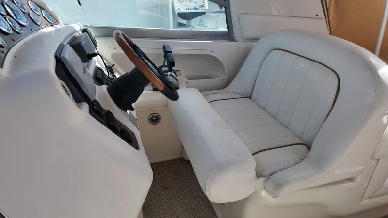 Slide: The Image of 2001 Sea Ray 290 Sundancer helm with white leather seat and wooden steering wheel. - 12