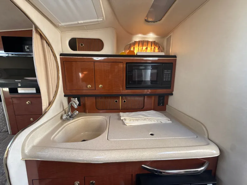 Slide: The Image of 2001 Sea Ray 290 Sundancer interior kitchen with sink, microwave, and storage cabinets. - 21