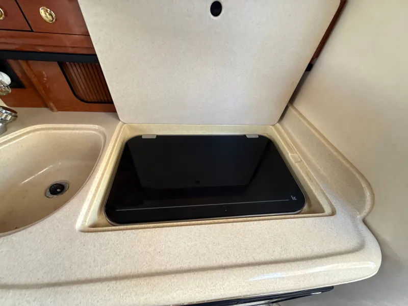 Slide: The Image of 2001 Sea Ray 290 Sundancer kitchen area with sink and covered stove. - 32