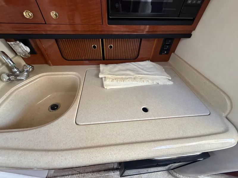 Slide: The Image of 2001 Sea Ray 290 Sundancer galley with sink, countertop, and storage cabinets. - 33
