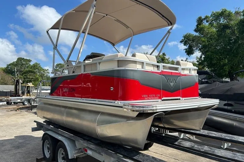 The Image of 2025 Avalon VENTURE CRUISE pontoon boat on trailer, red and gray design, sunny day. - 1