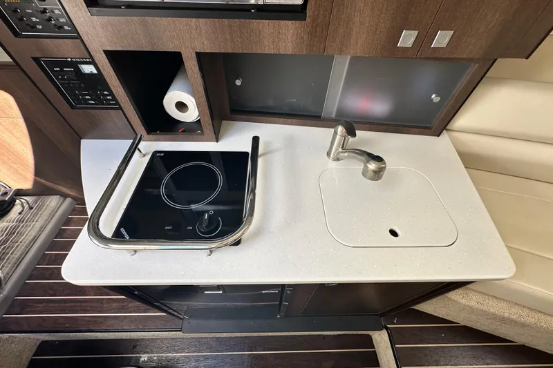 Slide: The Image of 2016 Monterey 295 Sport Yacht interior with kitchenette, featuring microwave, sink, and compact fridge. - 61