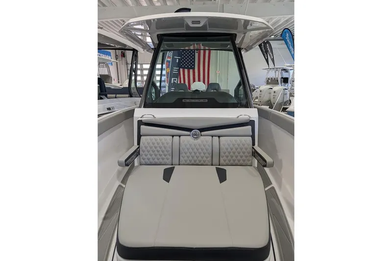 Slide: The Image of 2026 Monterey Elite 25 OB boat interior with cushioned seating and American flag backdrop. - 25
